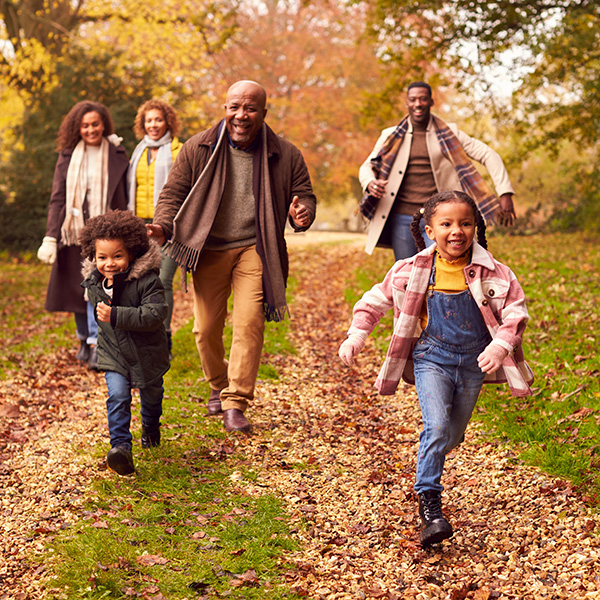 Smiling Multi-Generation Family Having Fun With Children Walking Through Autumn Countryside Together