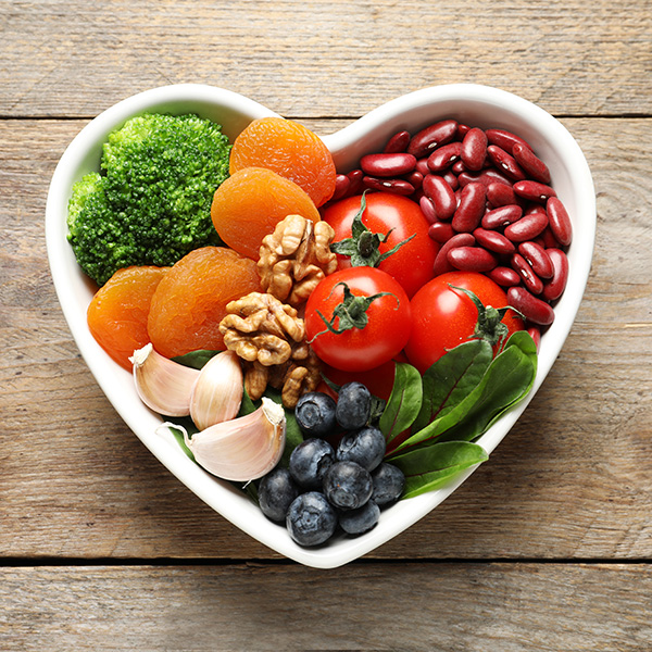 Bowl with products for heart-healthy diet on wooden background, top view