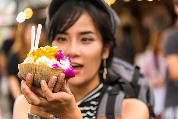 Girl holding a coconut ice cream and toppings